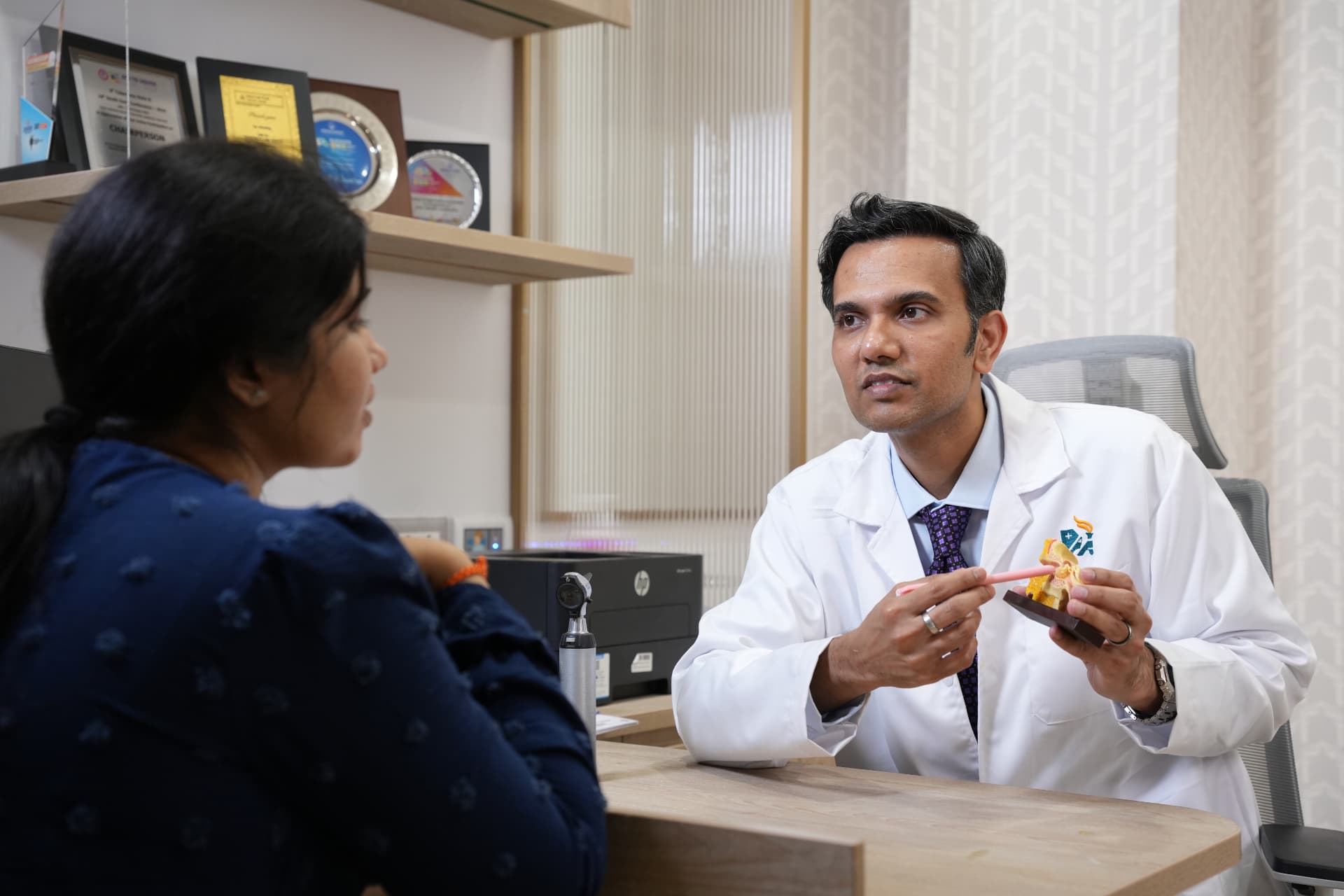 Dr. Sandeep Dachuri explaining an ear model to a patient during consultation